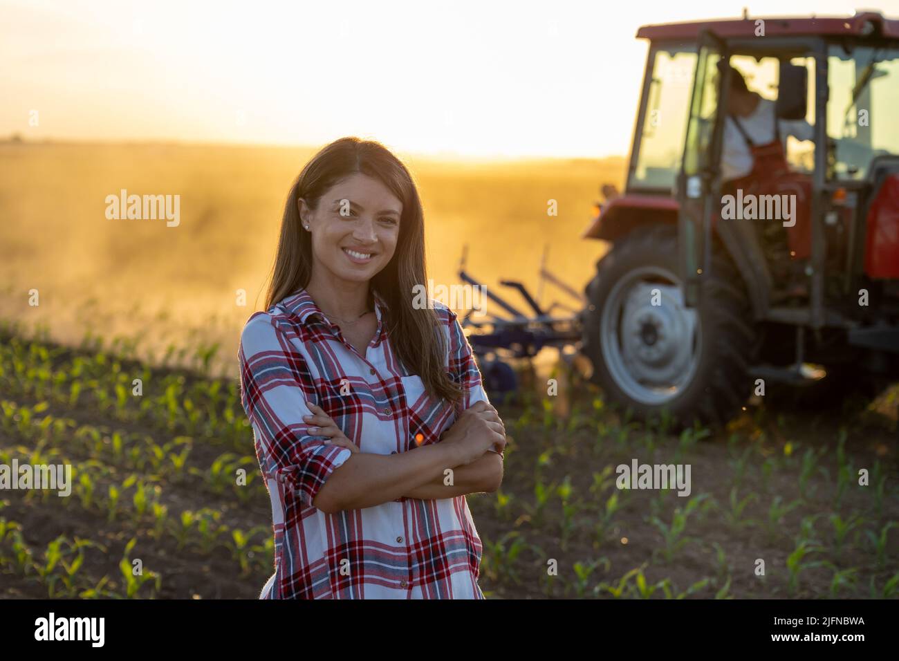 Portrait of pretty young farmer woman standing with crossed arms in ...