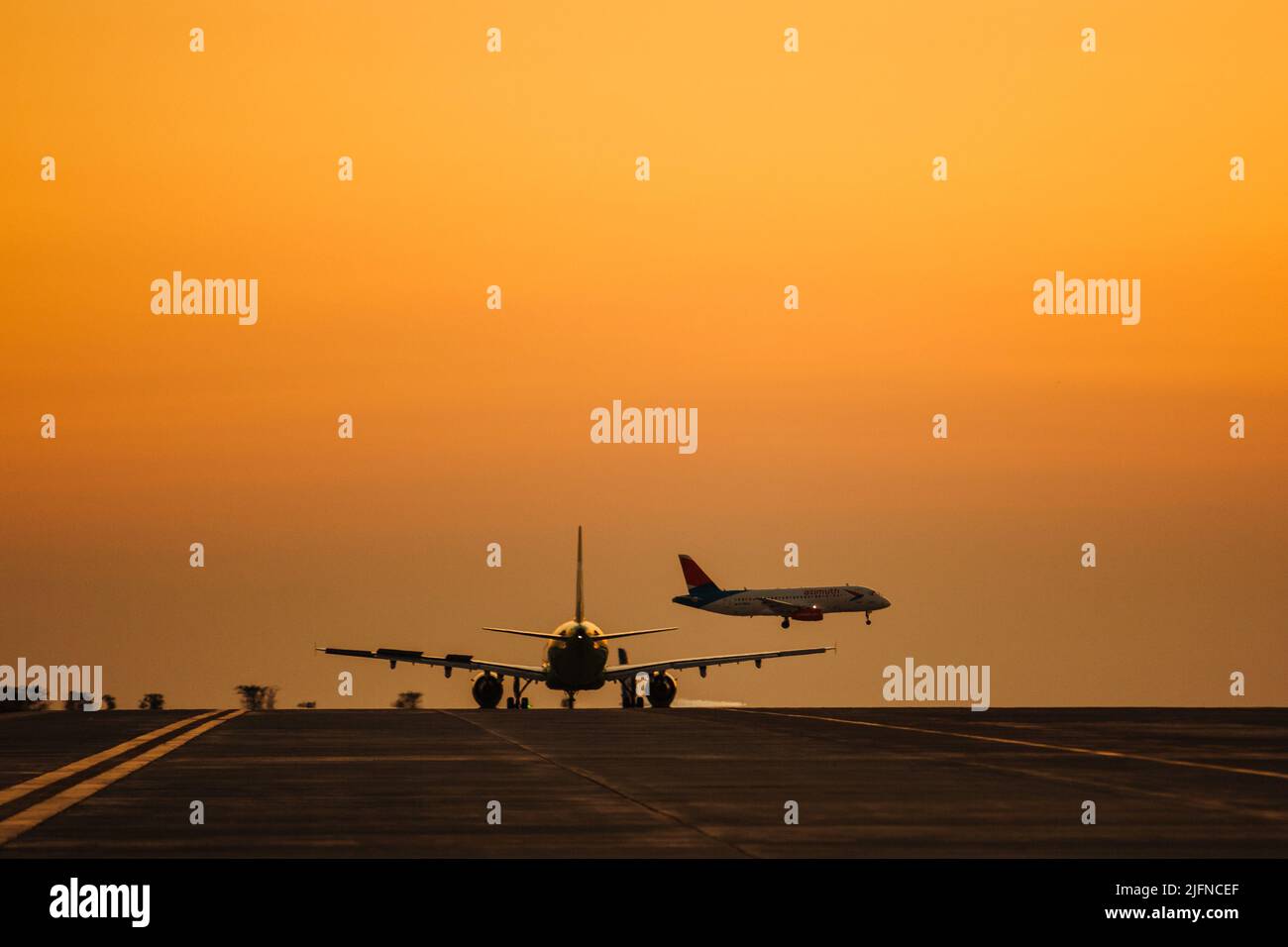 Passenger airplane take off from airport runway against the backdrop of a picturesque evening sky with sun rays. Stock Photo