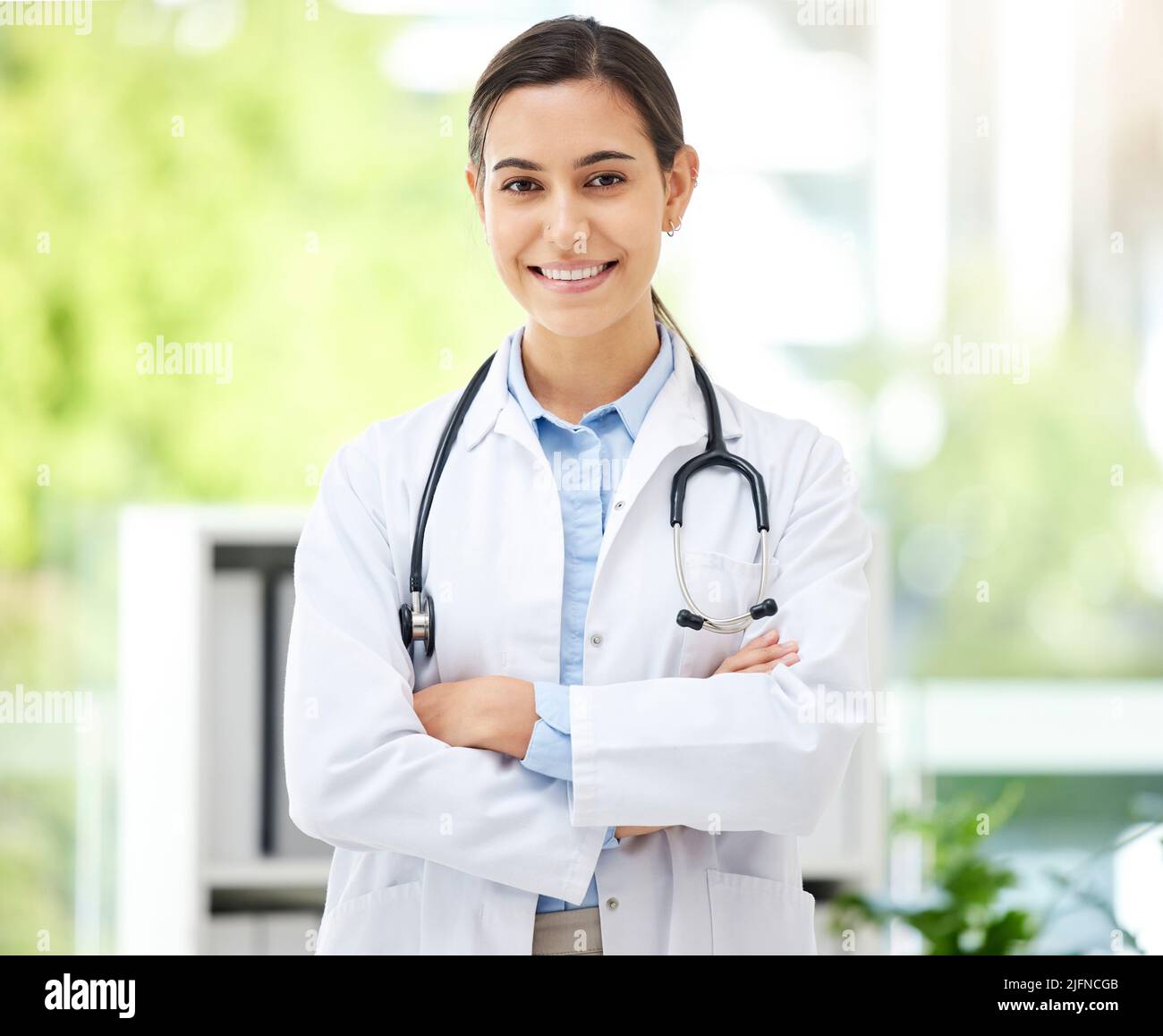 Confident young mixed race female doctor standing with her arms crossed ...