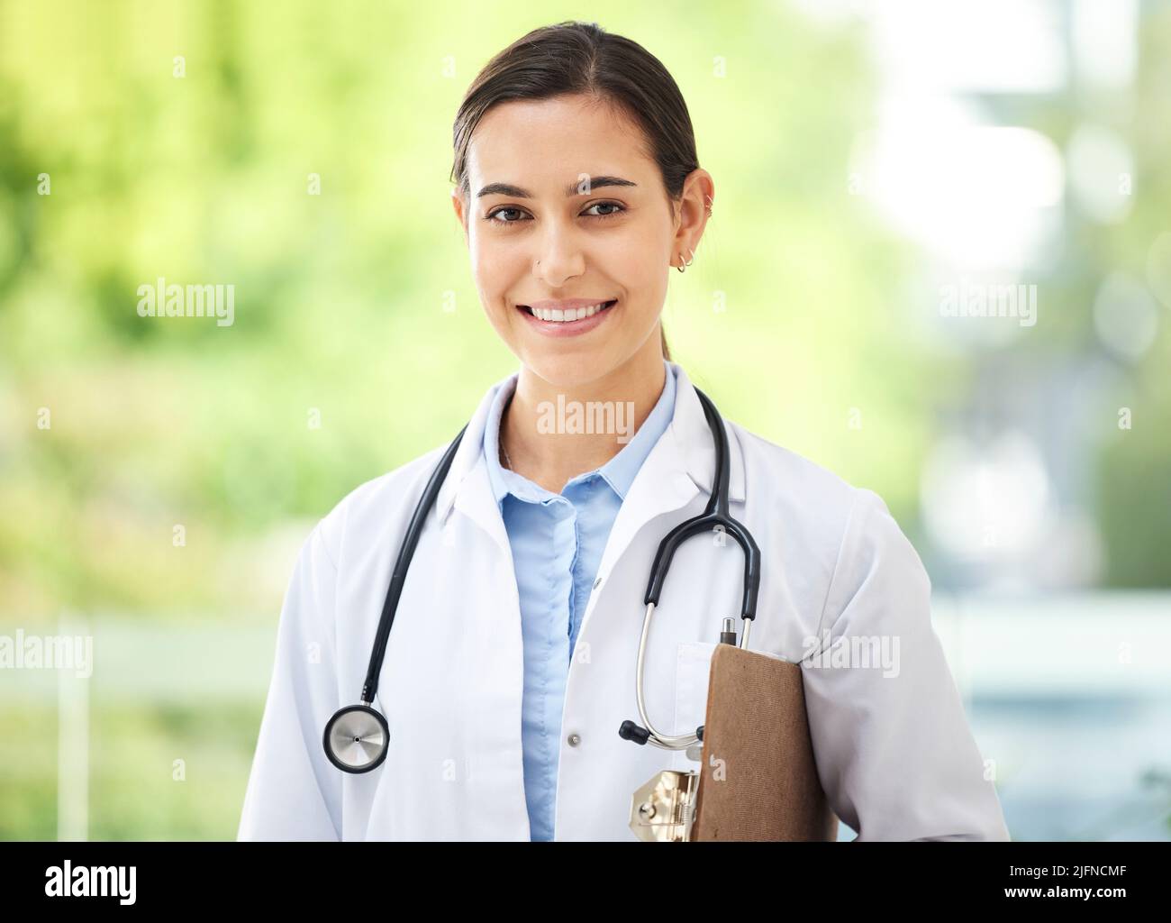 Confident young mixed race female doctor standing with clipboard a ...