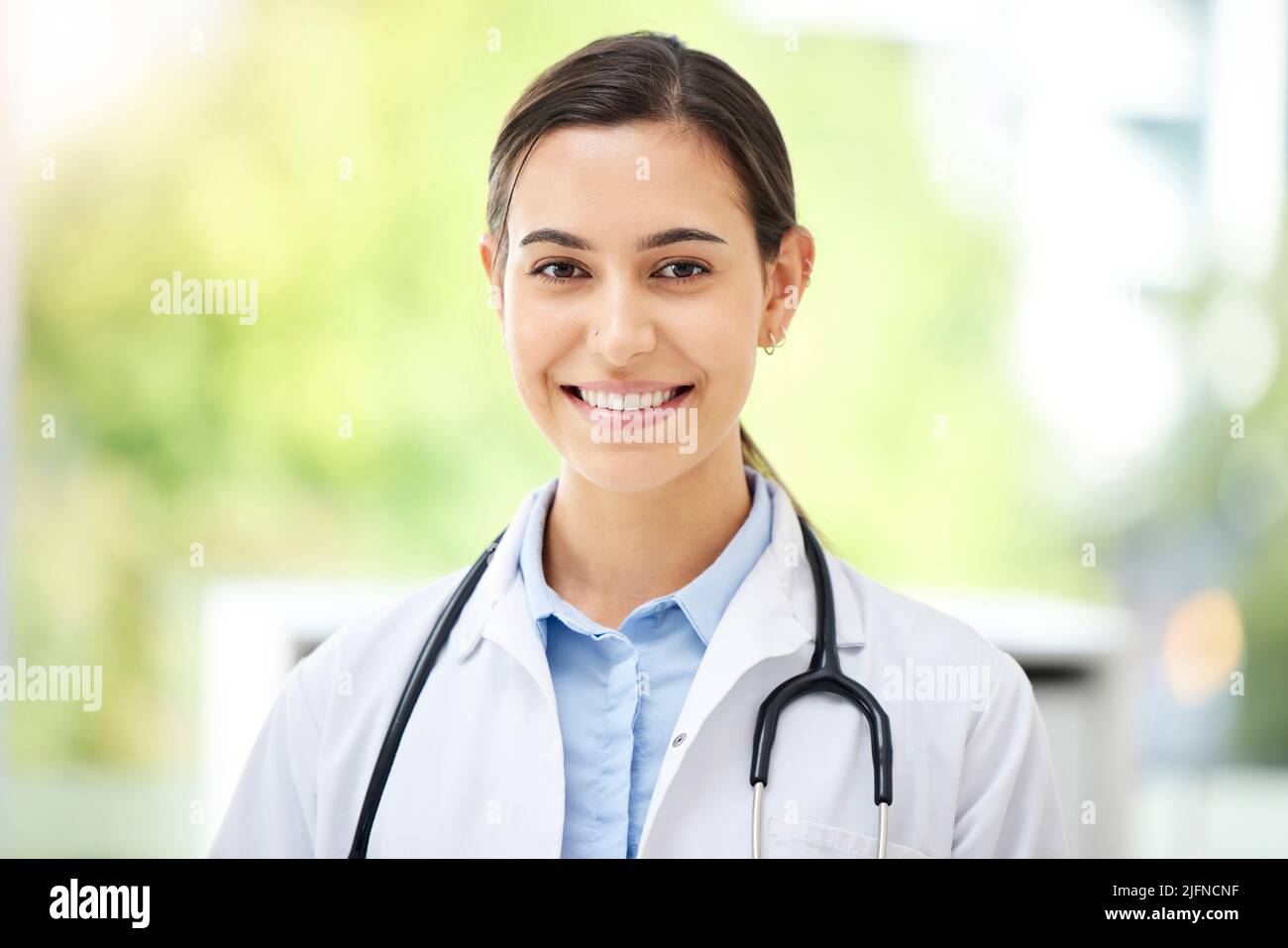 Confident young mixed race female doctor standing and smiling inside a