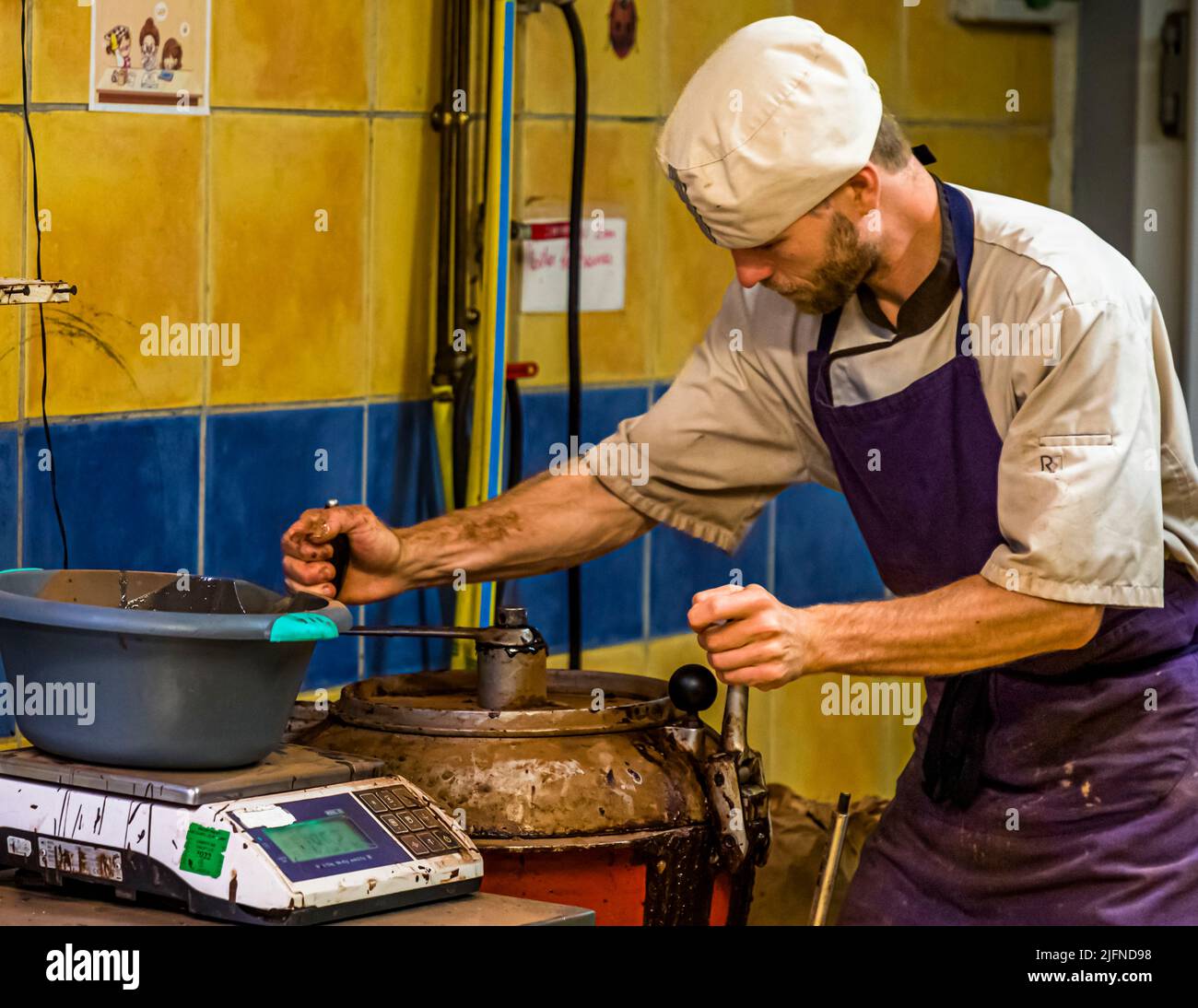 An employee of Chocolaterie Frigoulette closes the mélangeur in which the weighed marrows are mixed and heated. Frigoulette does not use animal fats such as milk, cream or butter. Palm oil is not used either. Instead, 68 percent cocoa and real cocoa butter from São Tomé Stock Photo