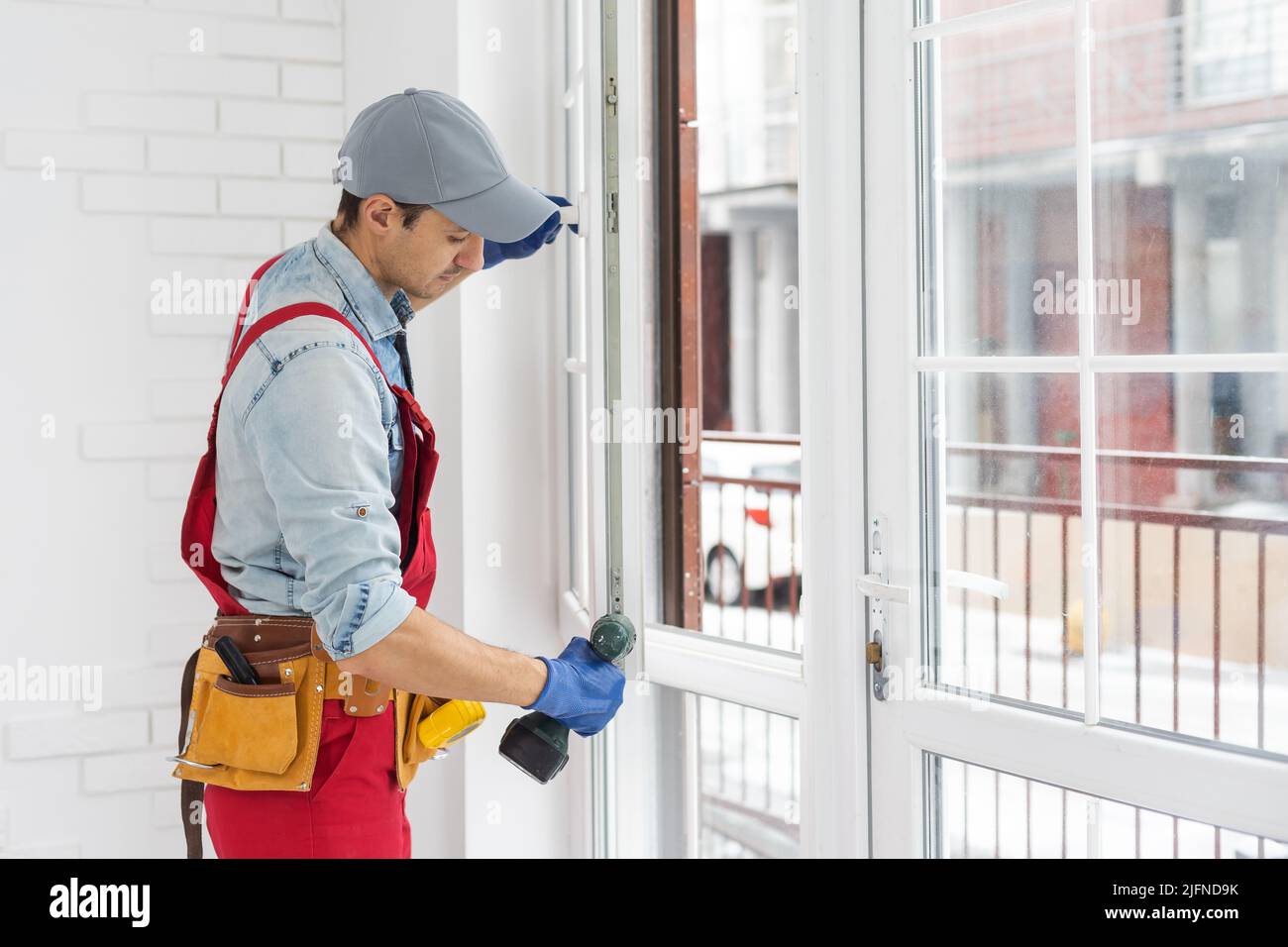 handyman adjusting white pvc plastic window indoors. worker using