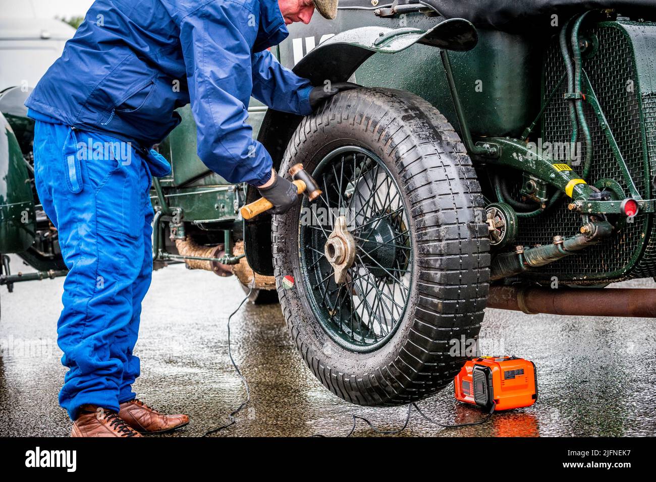 Mechcanic using a copper hammer to fix wheel nut to a vintage Bentley 4.5 litre car in the rain. Stock Photo