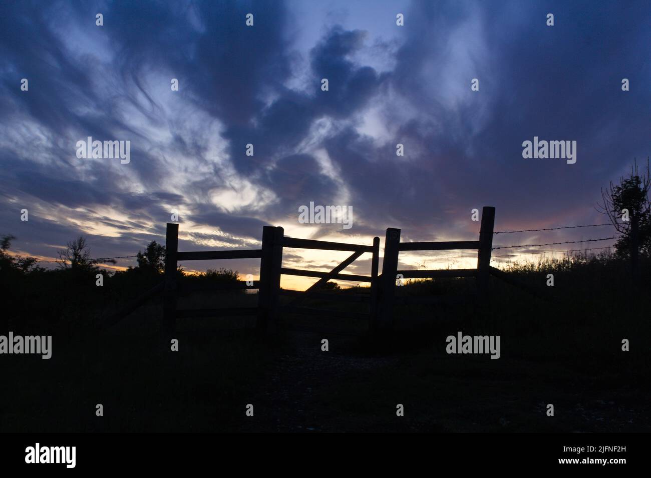 gate and fence silhouette at sunrise Stock Photo