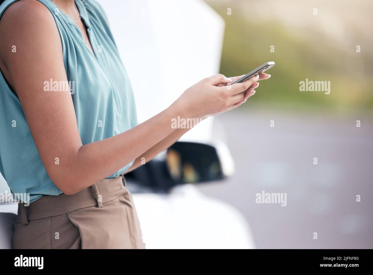 Closeup woman calling roadside assistance. Hands of a young woman dialling for help after a vehicle breakdown. Having car trouble and in need of a Stock Photo