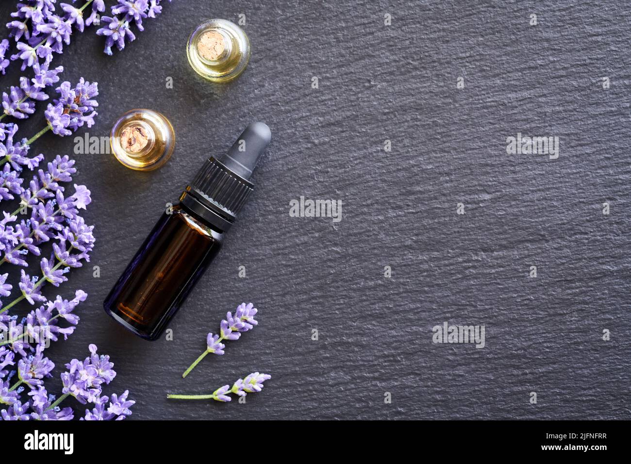 Dark background with bottles of essential oil with fresh blooming ...