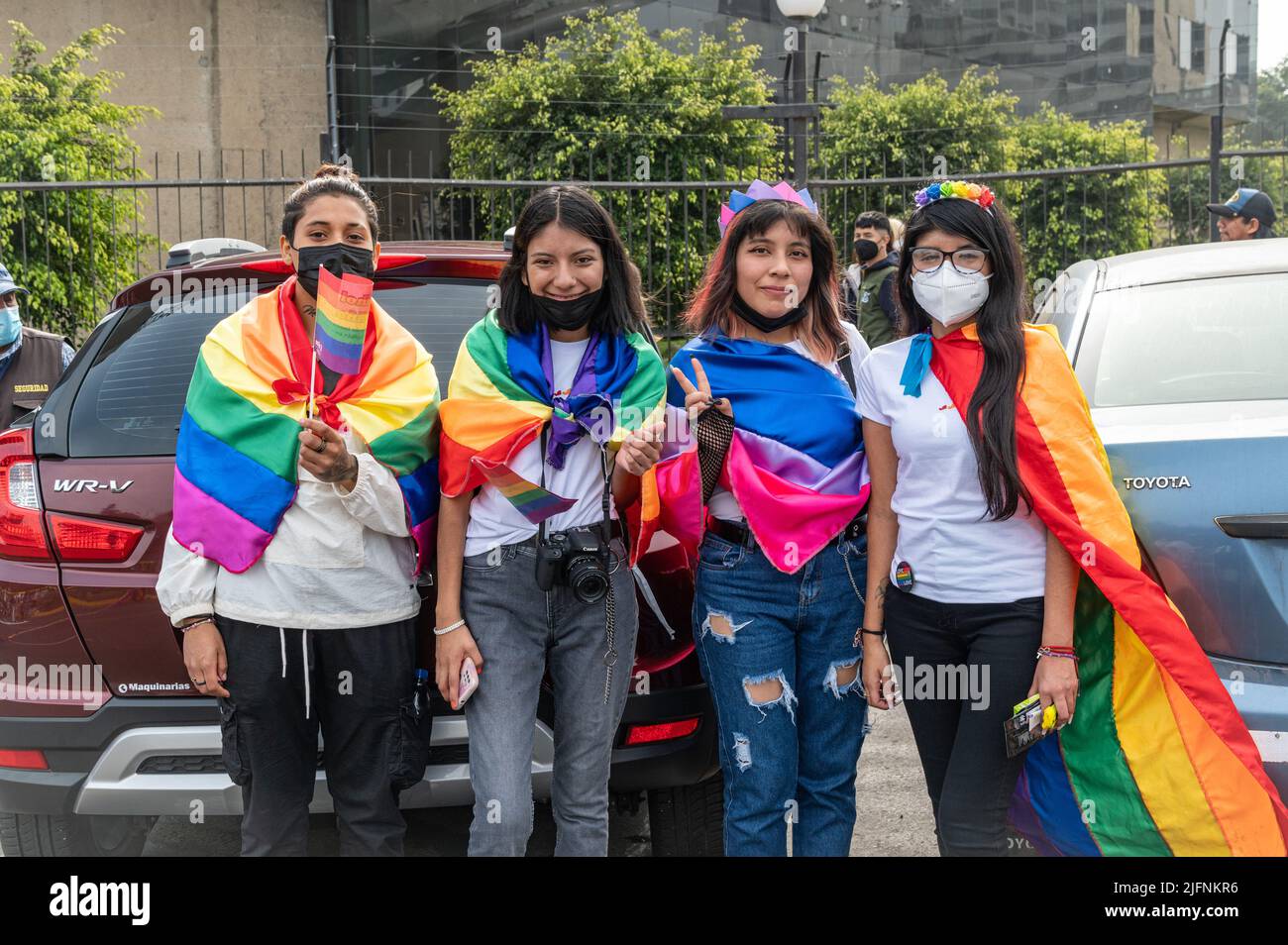 Photo of a group of young Latinx people posing with rainbow and bisexual flag capes at Lima's Marcha del Orgullo, the city's annual Pride march event. Stock Photo