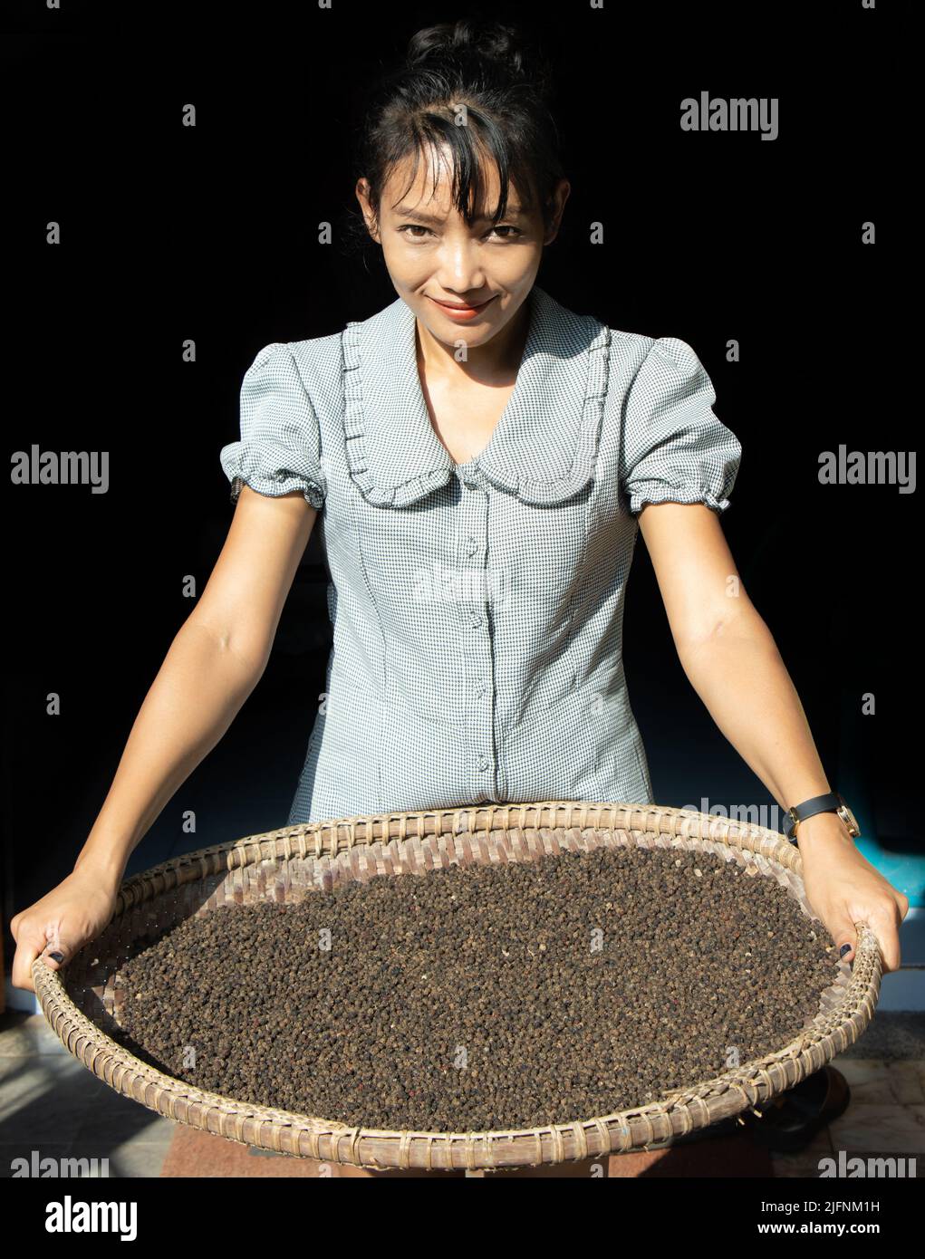Young woman holding a tray with dried black pepper Stock Photo