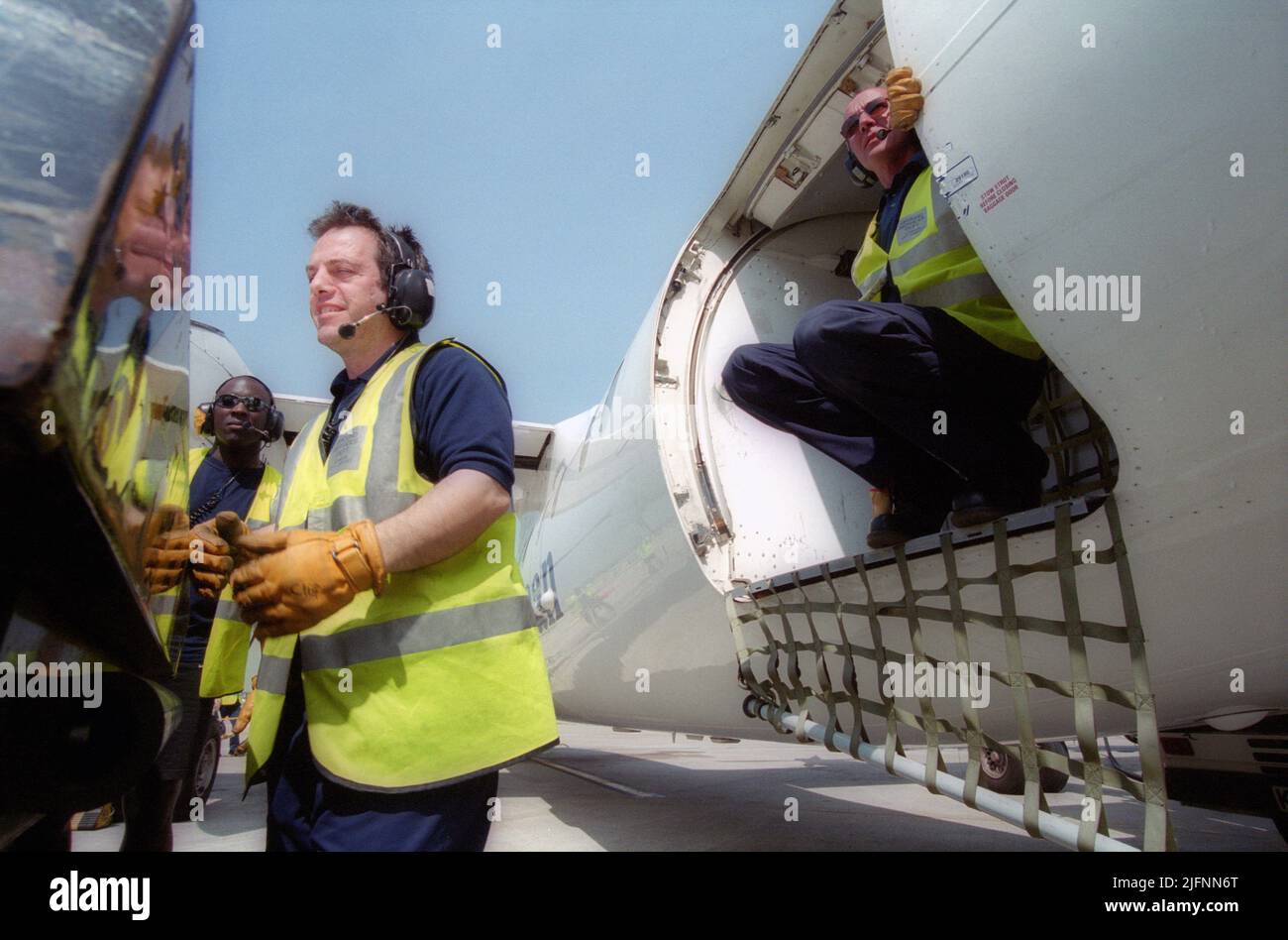 Airport luggage handlers unloading and transporting airline passengers luggage at an airport Stock Photo