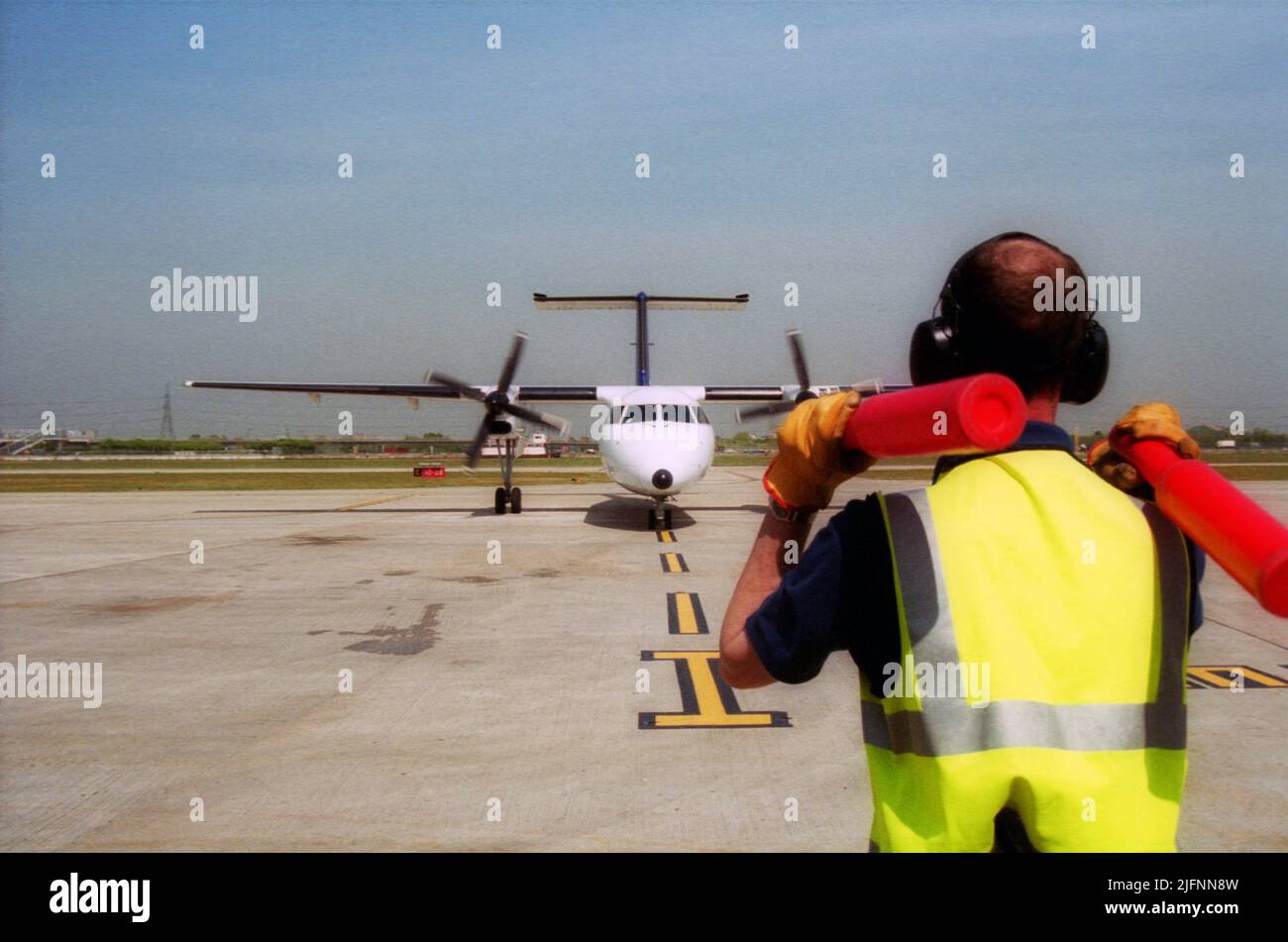 London City Airport aircraft marshal guiding airplane to the gate Stock Photo