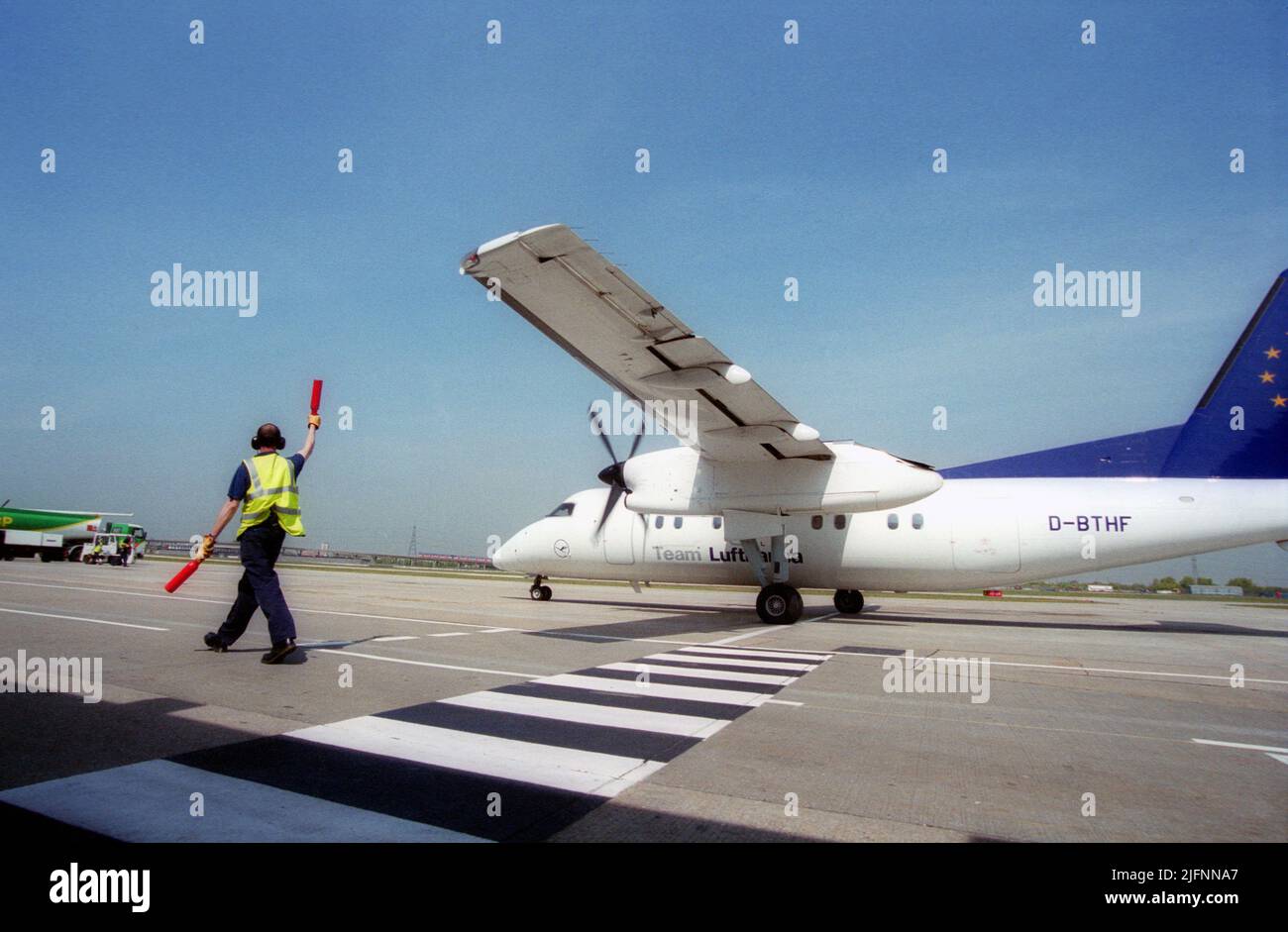 London City Airport aircraft marshal guiding airplane to the gate Stock Photo
