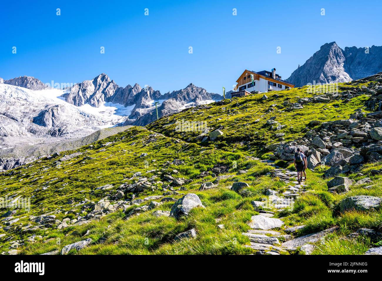 Two hikers ascending mountain hut Stock Photo - Alamy