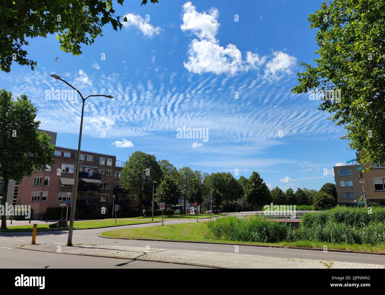 Rippled clouds named altocumulus undulatus over a neighbourhood in a Dutch town Stock Photo