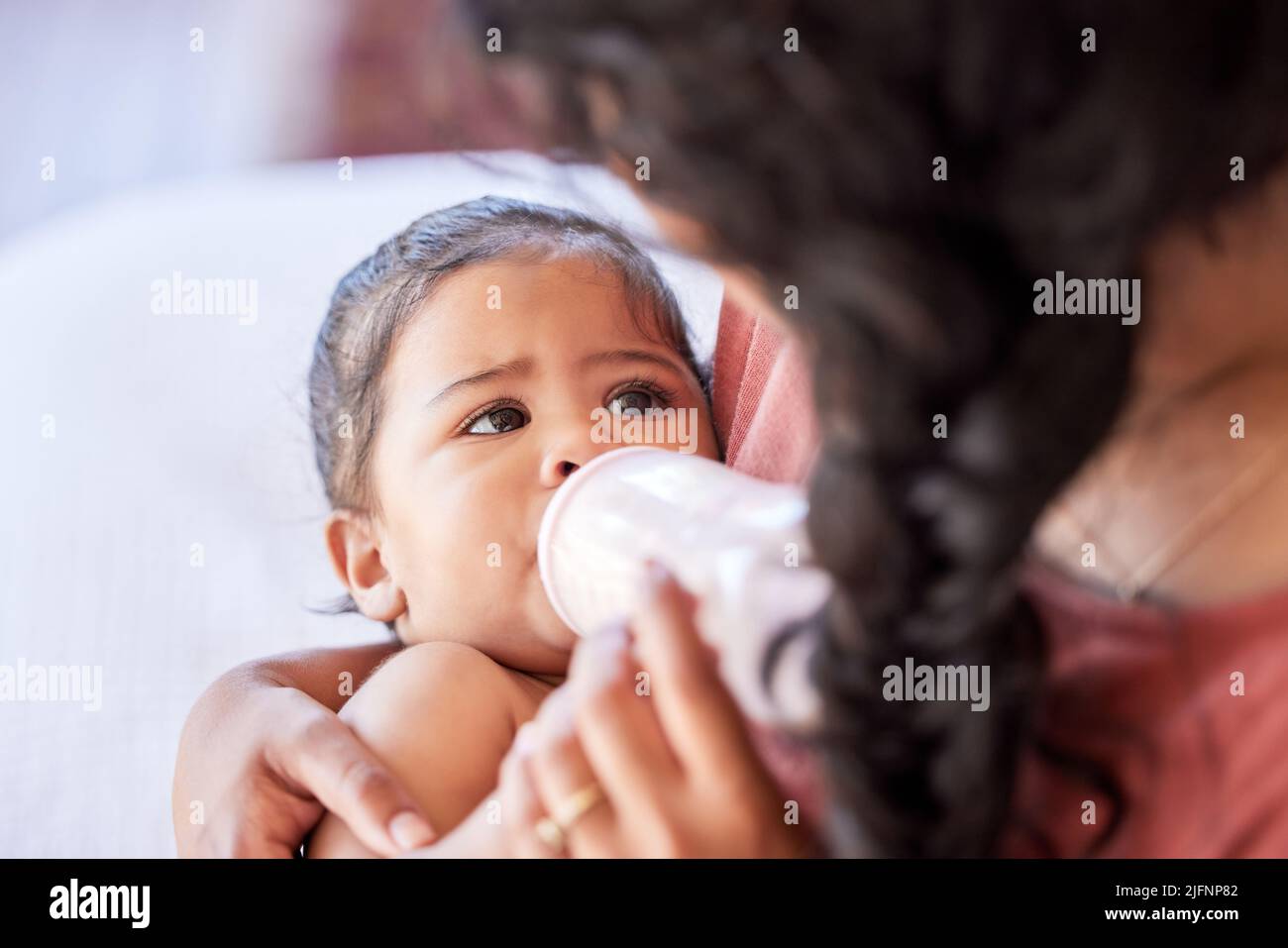 Hispanic mother feeding her little baby girl a bottle of milk formula