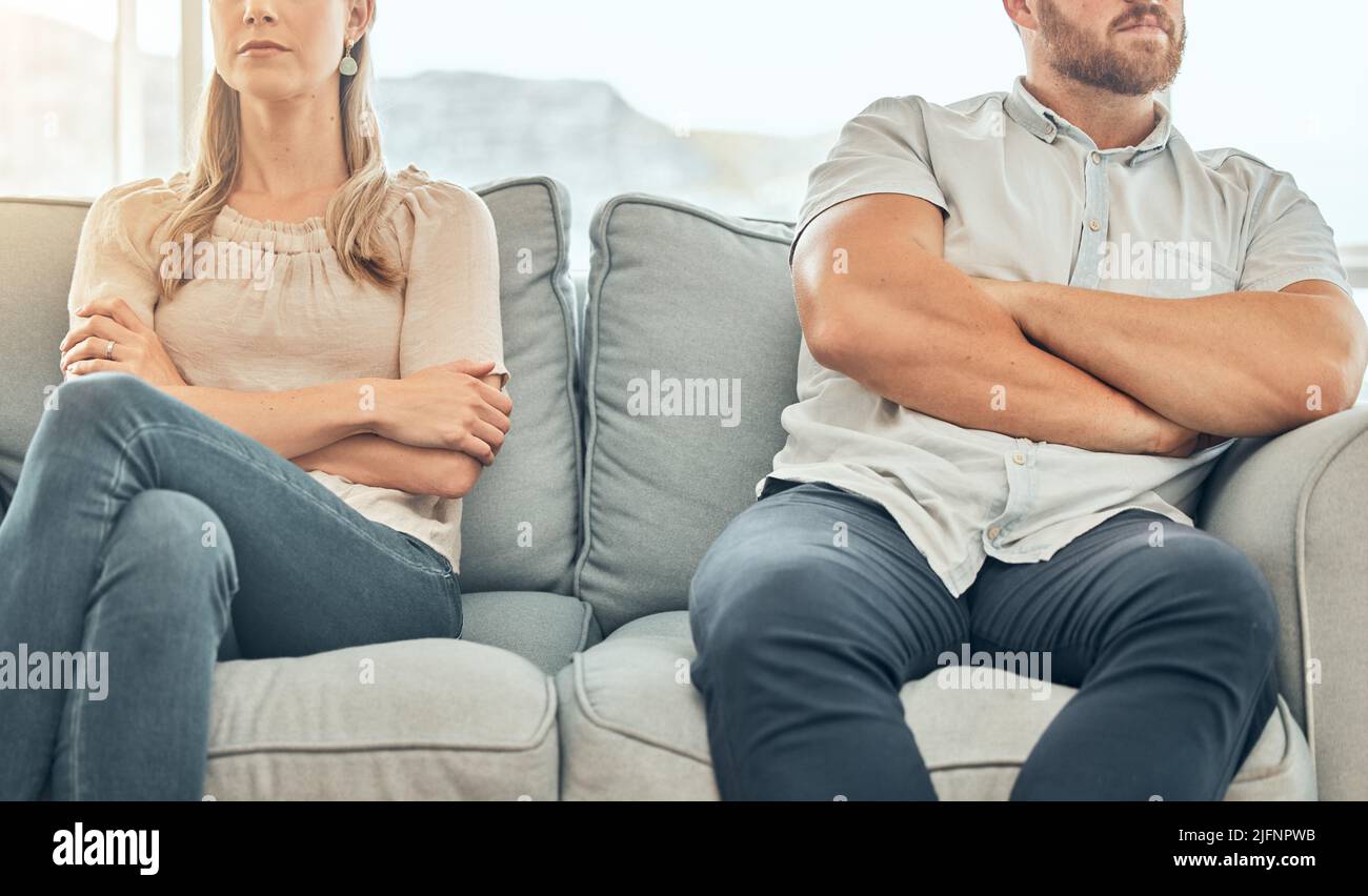Angry caucasian married couple sitting on couch arms folded to avoid