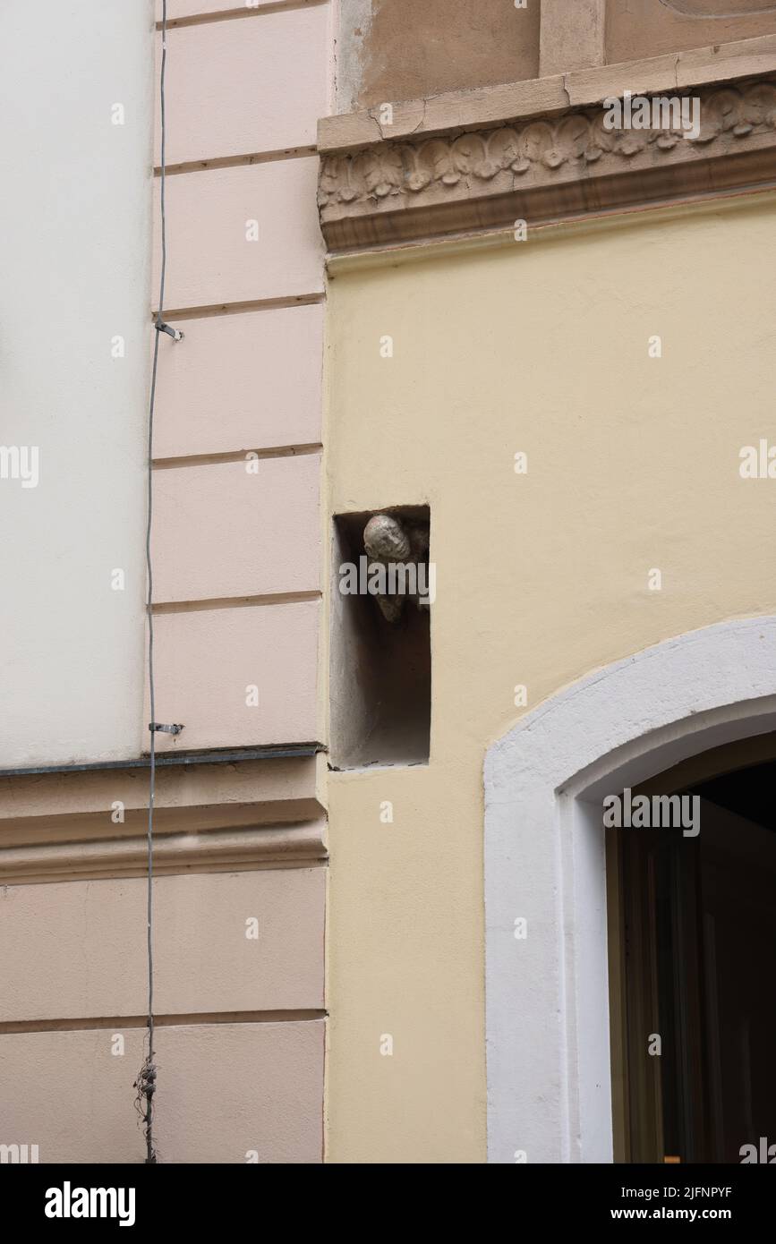 Small stone sculpture of man peeking out of his alcove in a wall; known in Slovak as Posmievačik, meaning “mockingjay” or “sneerer” Stock Photo