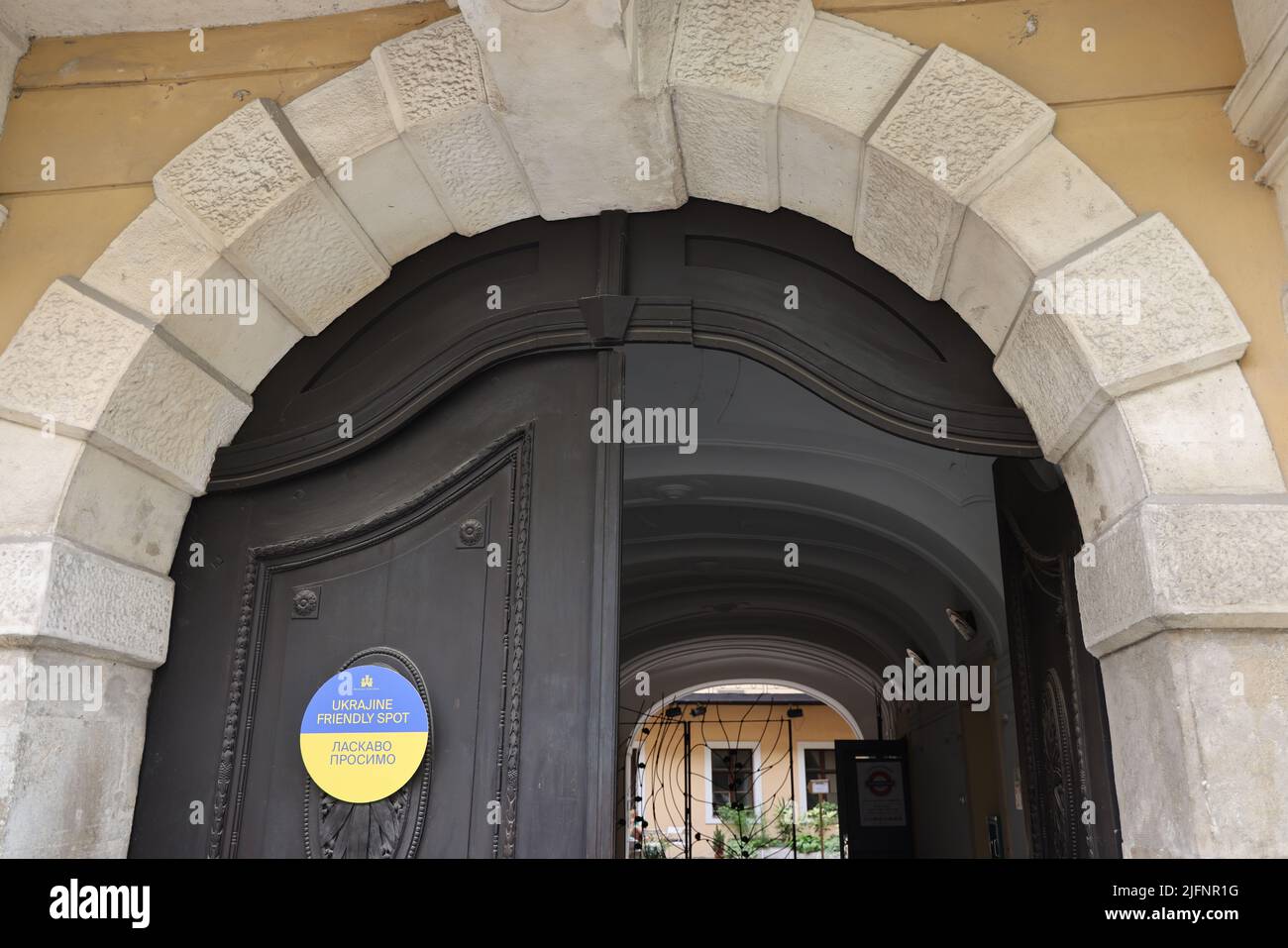 Doors with yellow-blue sign with text 'Ukrajine friendly spot - Ласкаво просимо', indicating that Ukrainian refugees are welcome in this venue Stock Photo