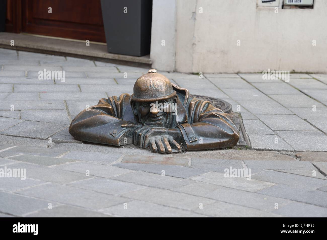 Quirky bronze statue (1997) of a sewer worker (Čumil, the watcher) emerging from a manhole in the center of Bratislava, Slovakia. Is he a peeping tom? Stock Photo