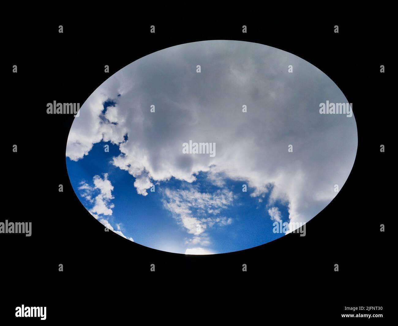 Blue sky with clouds seen through oval hole Stock Photo Alamy
