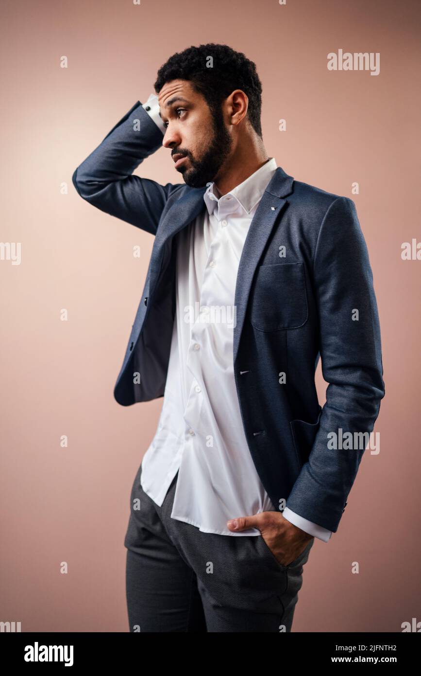 Serious young businessman posing in studio over beige background. Stock Photo