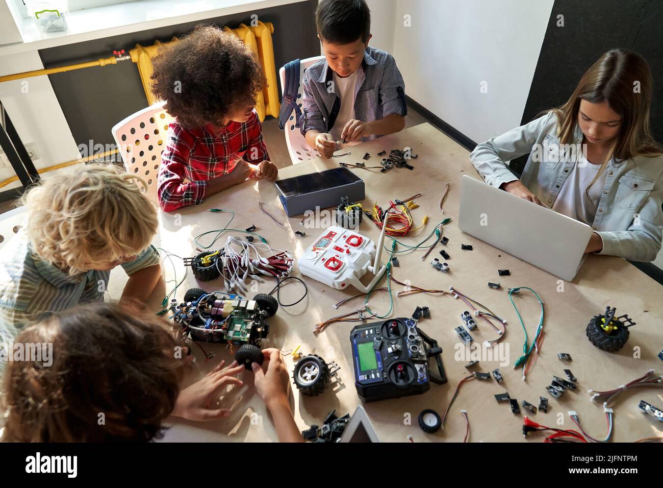 Group of multiracial schoolkids at stem class building robot. Table top view. Stock Photo