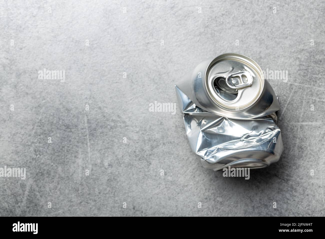Empty crumpled can on a gray table. Top view. Stock Photo