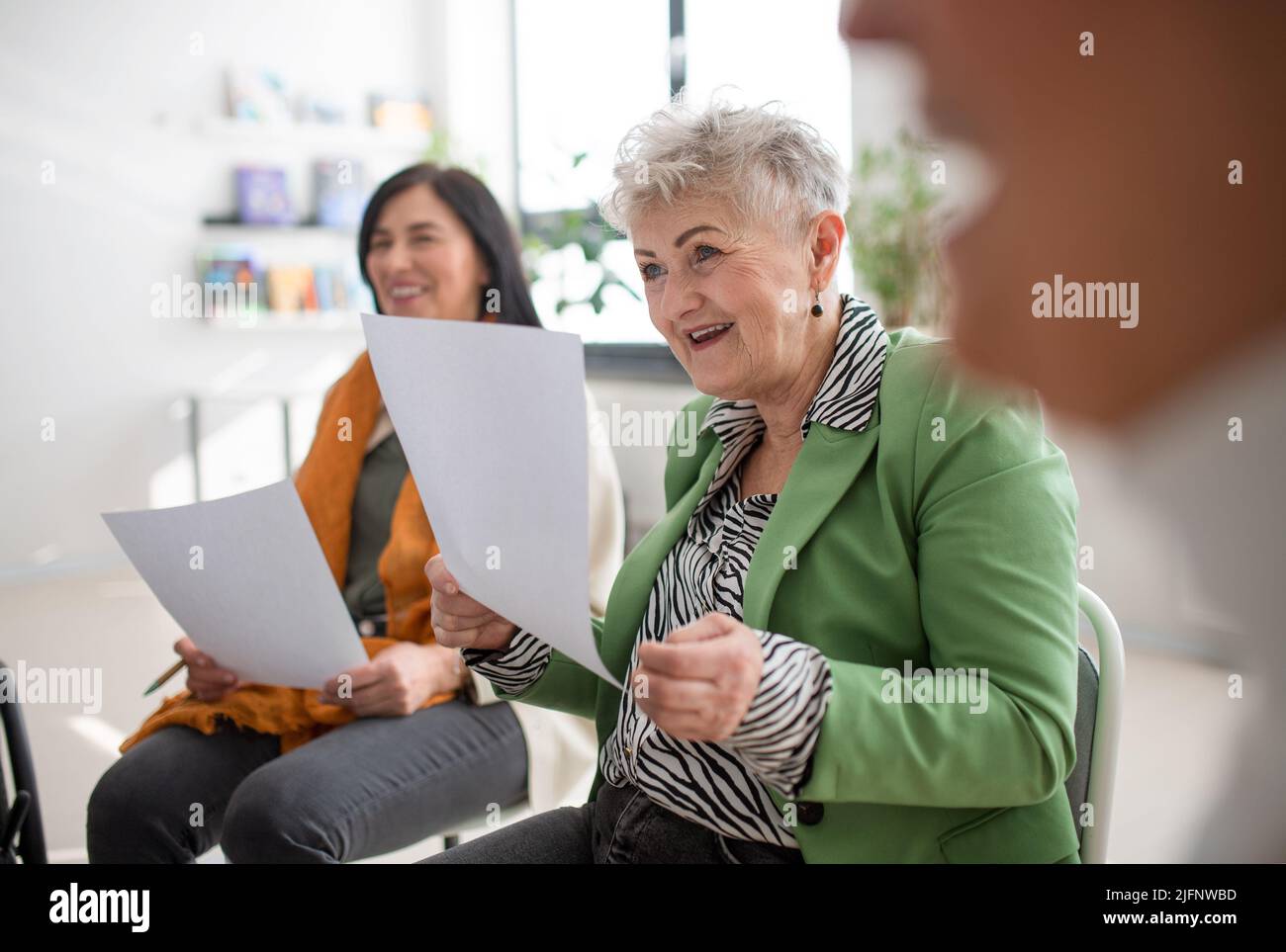Group of seniors with papers singing together at choir rehearsal. Stock Photo