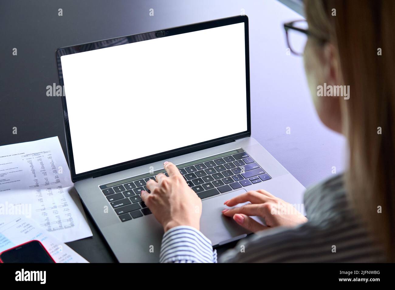 Young businesswoman typing on laptop computer keyboard with empty screen. Stock Photo