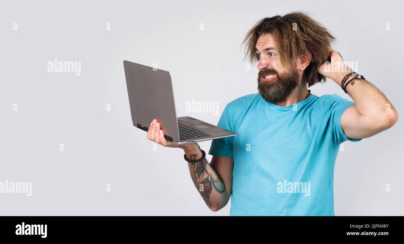 Confused man with laptop computer looking at display. Bearded male with notebook. Digital device. Stock Photo