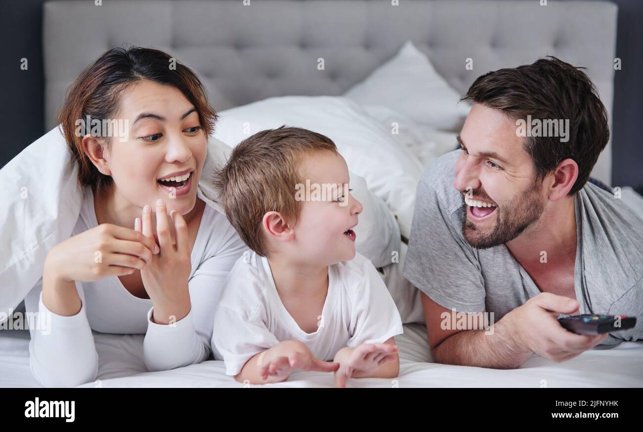 We learn from him every day. Shot of a young family watching tv together at home. Stock Photo