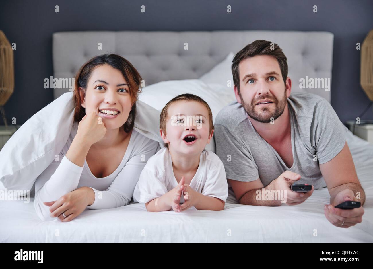 Glued to the tv for the day. Shot of a young family watching tv together at home. Stock Photo