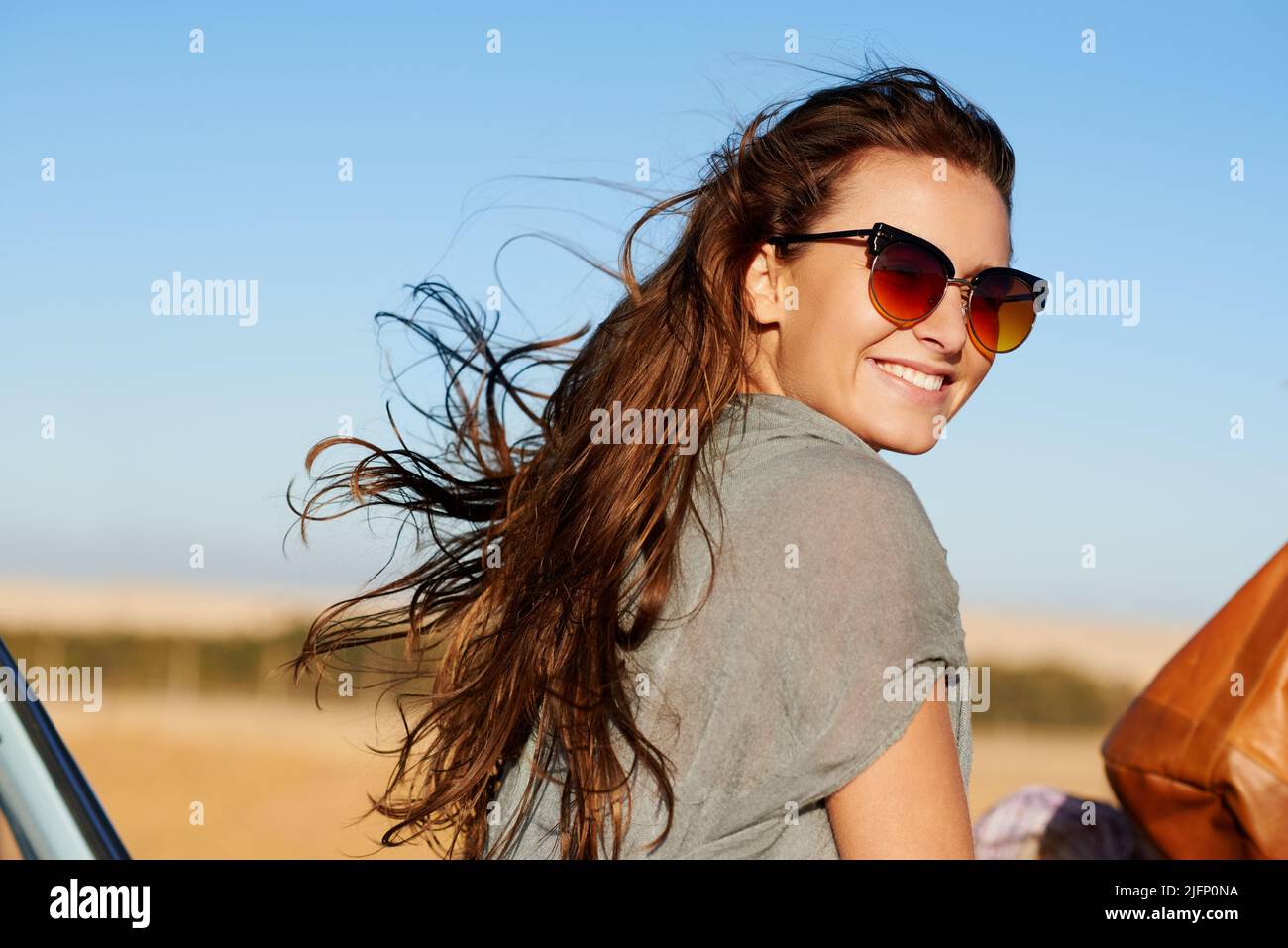 Lifes as real as it gets on the open road. Portrait of attractive young woman smiling wearing horn rimmed sunglasses. Stock Photo