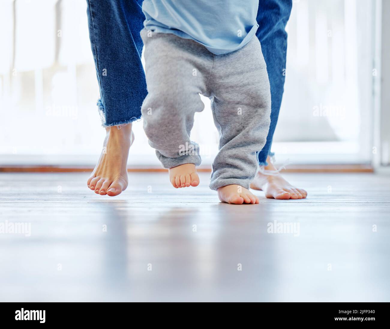 Soon hell be walking on his own. Cropped shot of an unrecognizable little boy learning to walk with the help of his mother at home. Stock Photo
