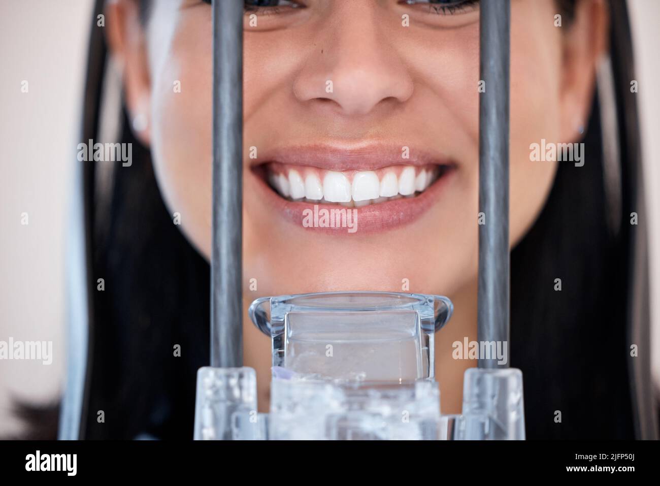 Closeup of a woman getting a digital x-ray scan of her mouth at the dentist. One female only smiling for a dental checkup. Patient taking care of her Stock Photo