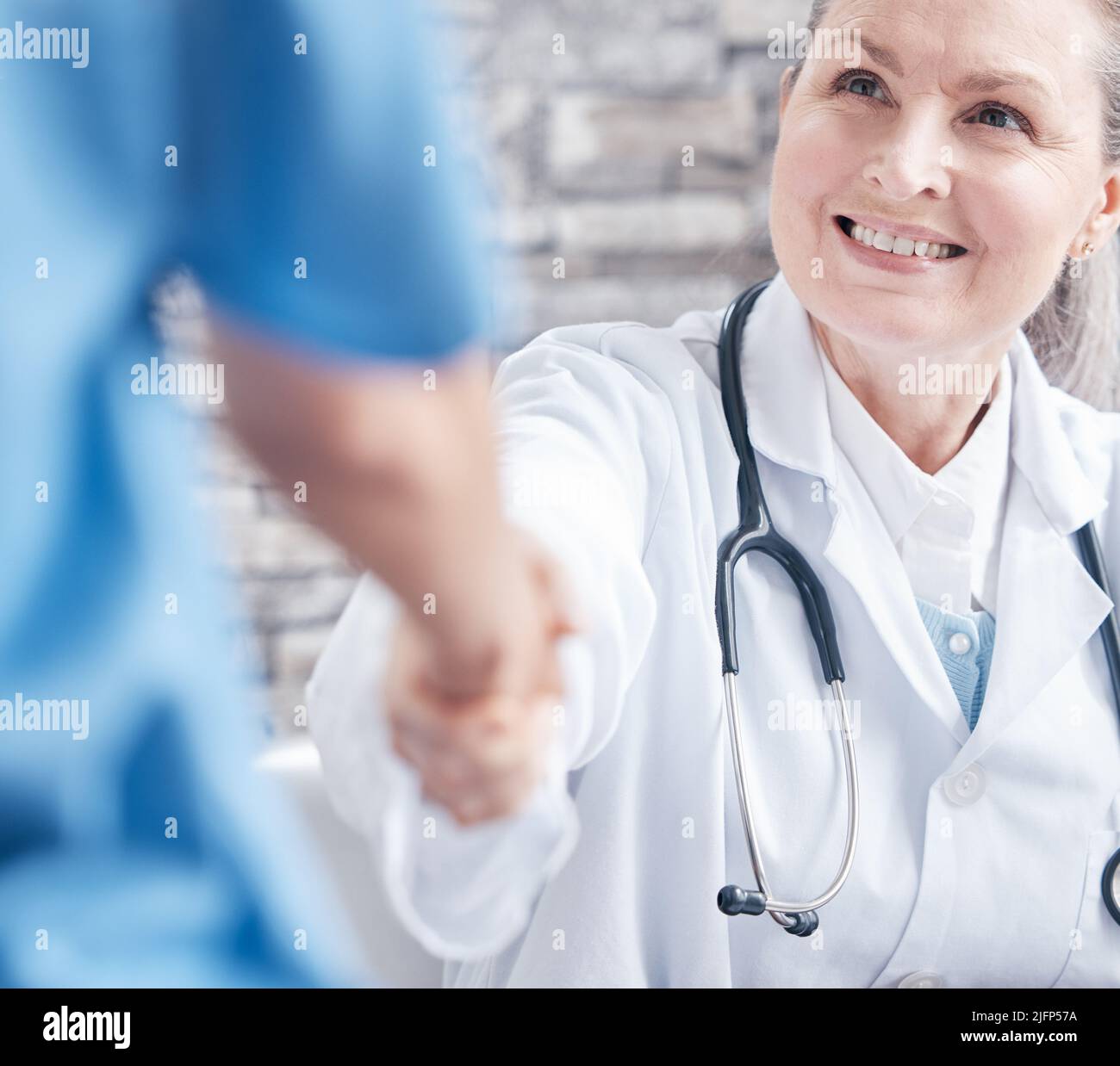 Thank you for assisting me in this medical procedure. Shot of a doctor shaking hands with a colleague in a medical office. Stock Photo
