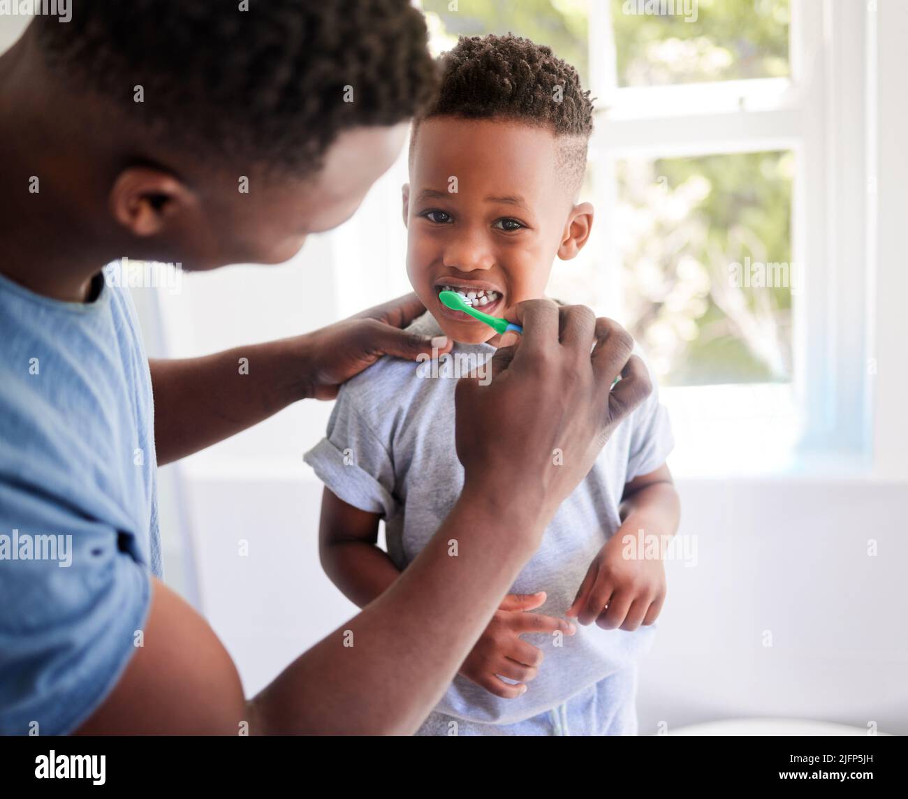 Dads showing me how to brush properly. Shot of a father brushing his sons teeth in the bathroom at home. Stock Photo