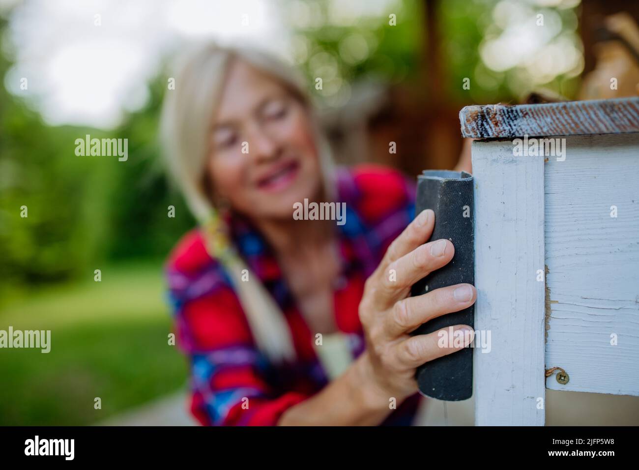 Senior woman cleaning and renovating garden furniture and getting the