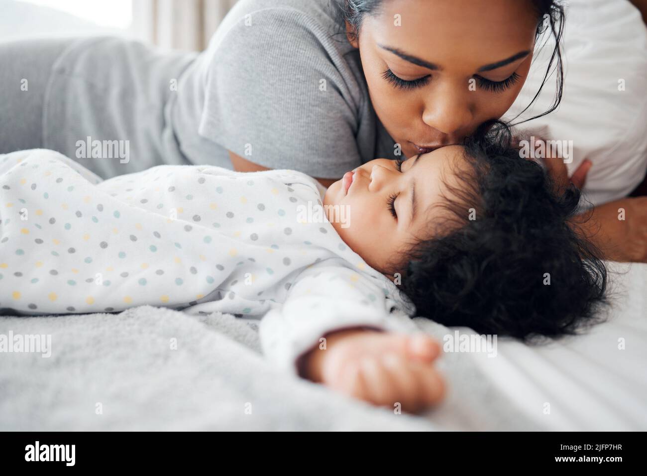 What a sweetheart. Shot of a young mother kissing her sleeping baby. Stock Photo
