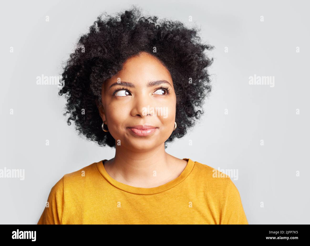 I didnt want to say anything. Shot of a young woman looking away while posing against a grey background. Stock Photo