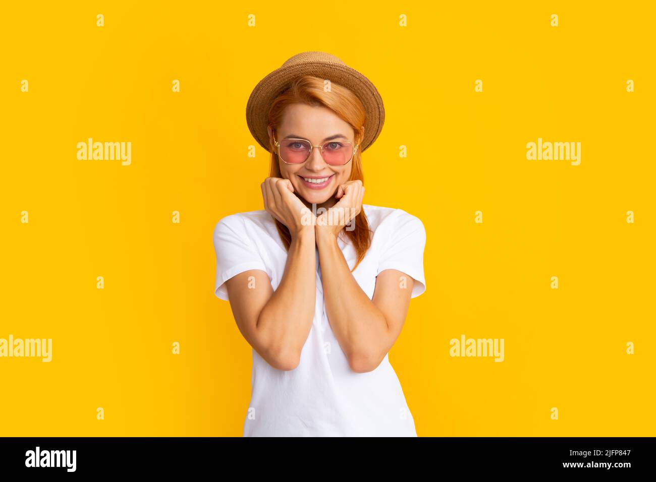 Smiling portrait of pretty young woman wearing sunglasses and straw hat ...
