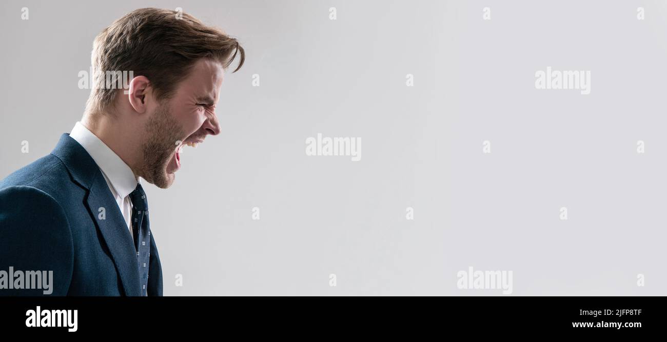 Yelling and screaming. Man face portrait, banner with copy space. Business man in suit, isolated studio background, banner poster. Angry man yell grey Stock Photo