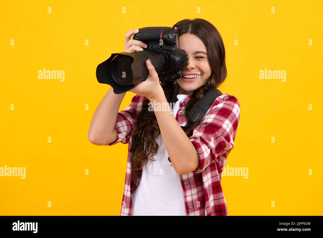 12, 13, 14 year old teen girl holding digital camera or DSLR over yellow background. Happy teenager, positive and smiling emotions of teen girl. Stock Photo