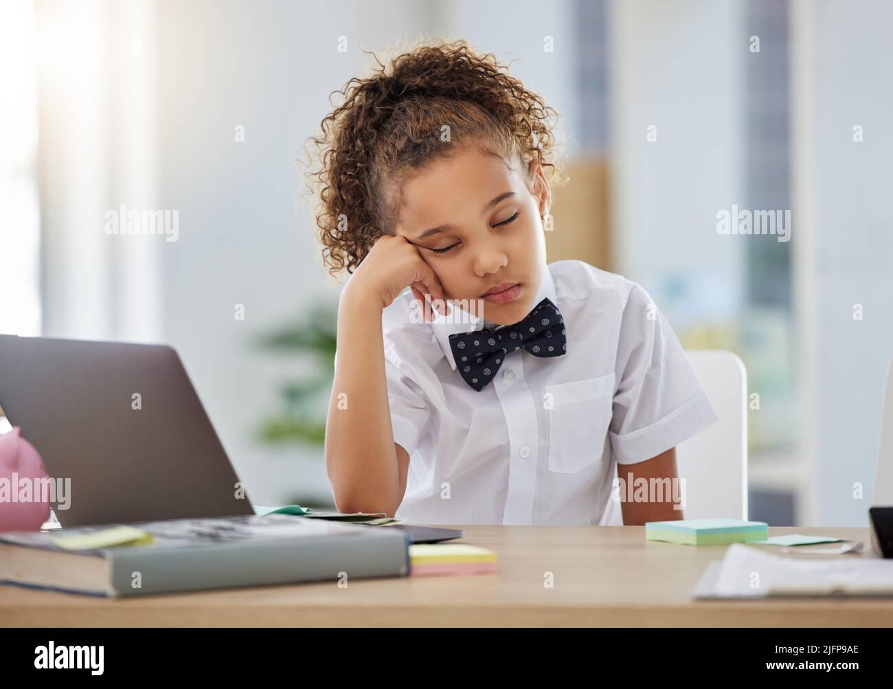 I missed my morning nap. Shot of an adorable little girl dressed as a businessperson sitting alone in an office and feeling sleepy. Stock Photo