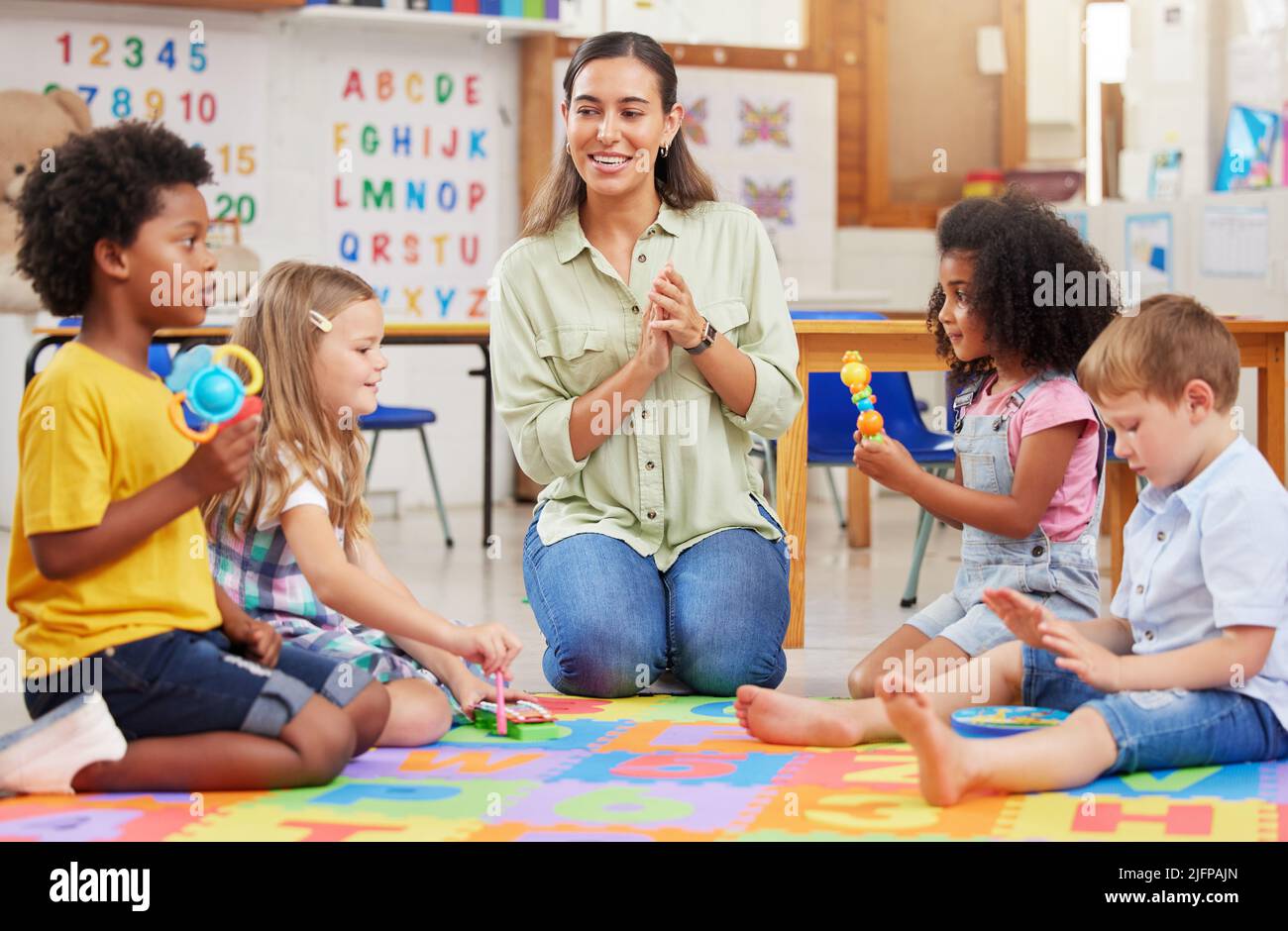 Our day is not complete without our favourite songs. Shot of a teacher singing with her preschool children. Stock Photo