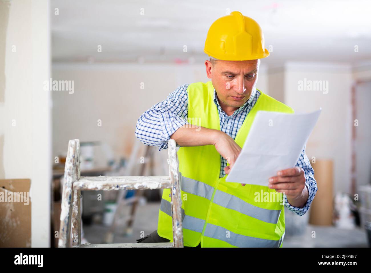 Man with documents in her hands stands in the middle of renovated room ...