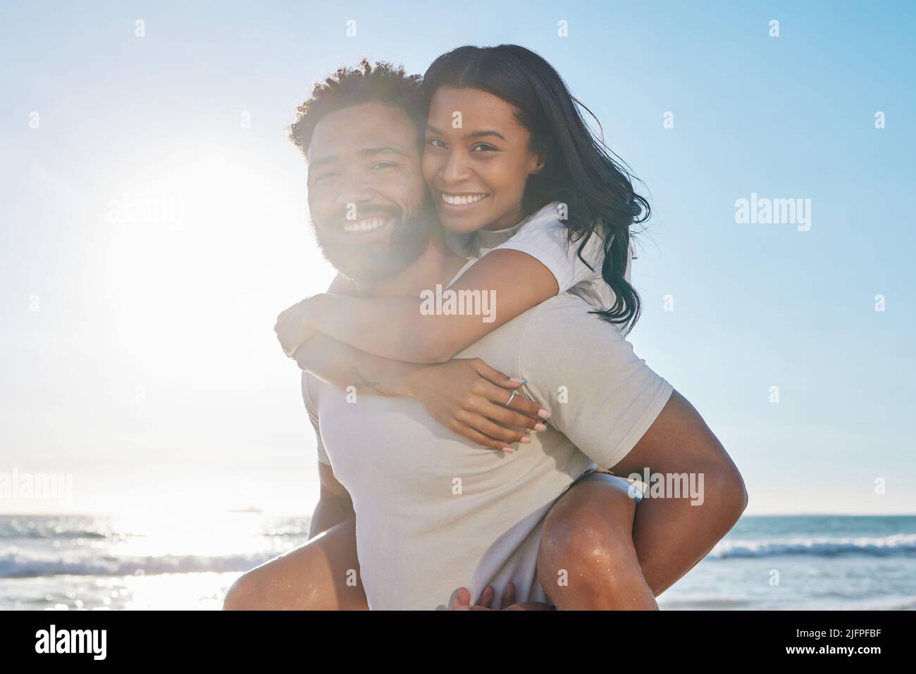 Bonding on the beach. Cropped portrait of a handsome young man piggybacking his wife on the beach. Stock Photo