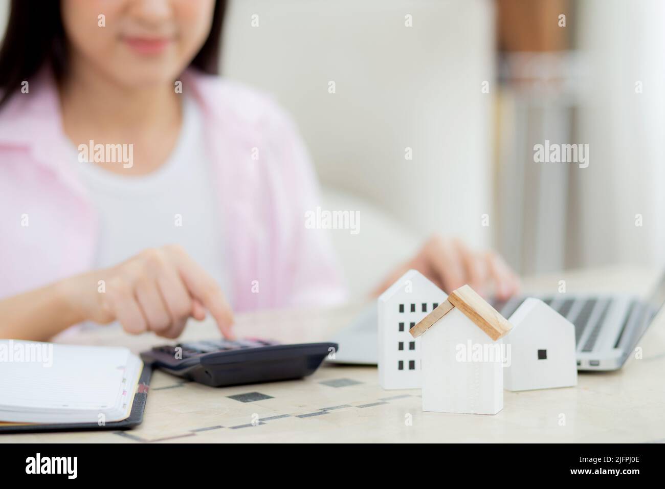 Closeup hands of woman sitting and planning and calculate expense and mortgage with calculator and home on desk, insurance and budget of residential, Stock Photo