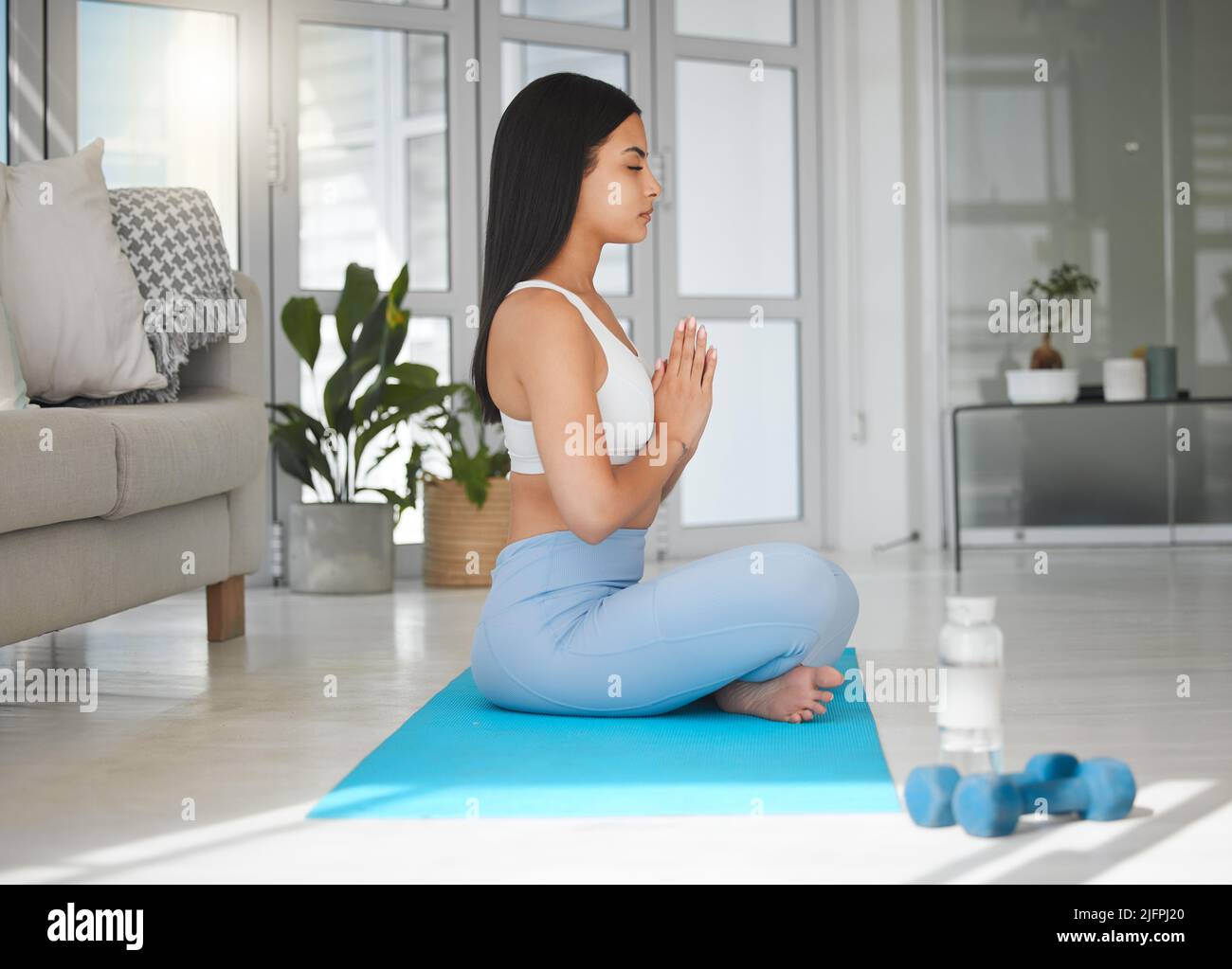 Meditate with mindful breathing. Shot of a sporty young woman meditating while practising yoga at home. Stock Photo