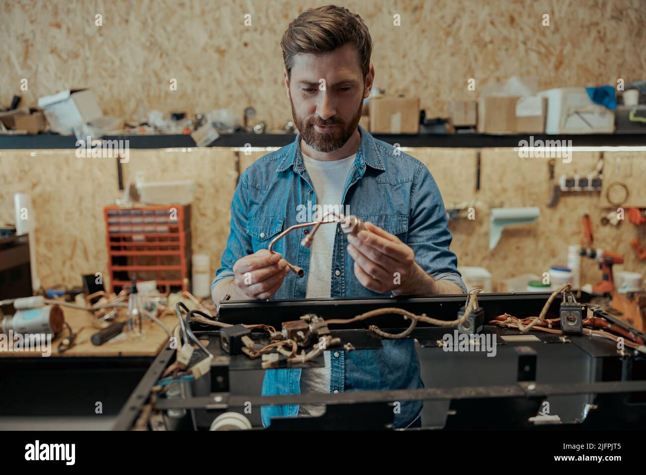 Smiling young worker repairing coffee machine in a workshop Stock Photo